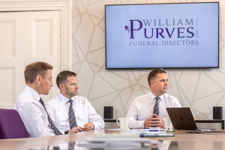 3 men in matching shirts and ties in the boardroom of a Scottish Funeral Directors'