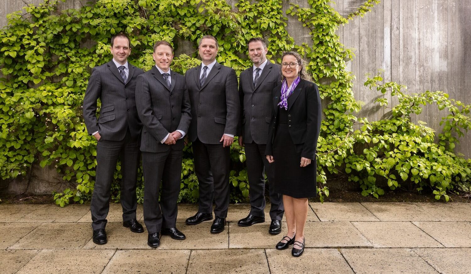 Five members of the William Purves staff, standing in front of a wall with leaves